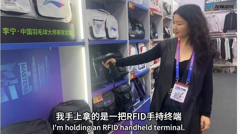 Inside a sports merchandise store at an event venue, a staff member using an RFID handheld terminal to read item tags